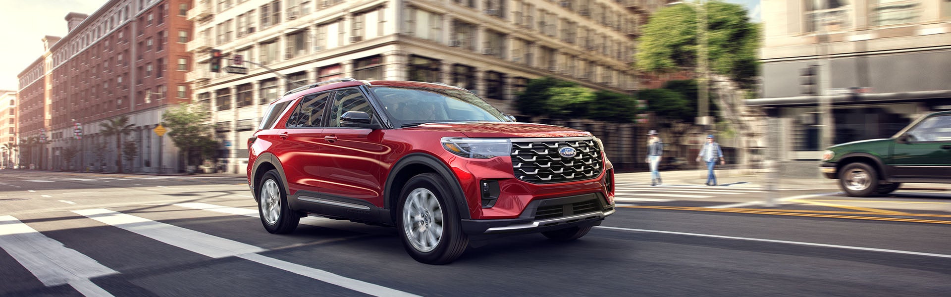 A Ford Explorer SUV driving through a city street with pedestrians nearby.